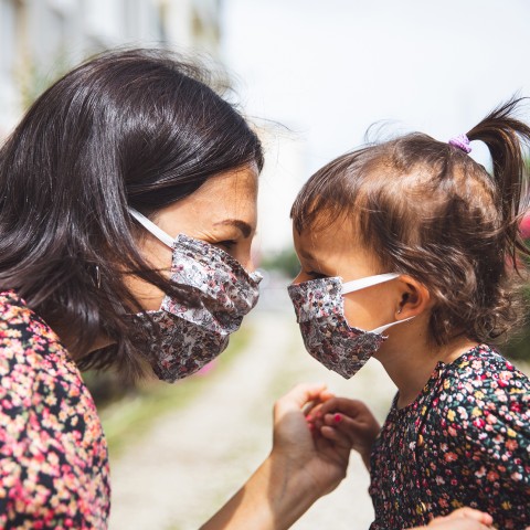 Mother and daughter looking eye-to-eye wearing masks