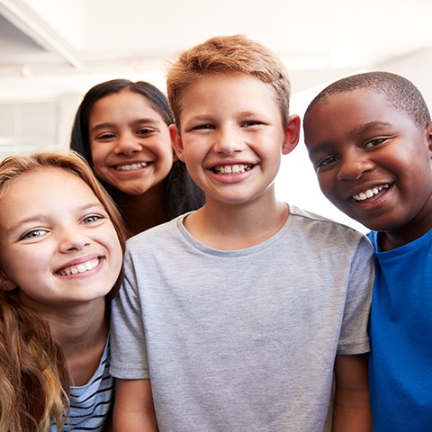 Group of diverse school-age children smiling. 