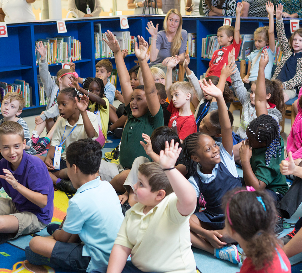 Classroom with students raising hands.