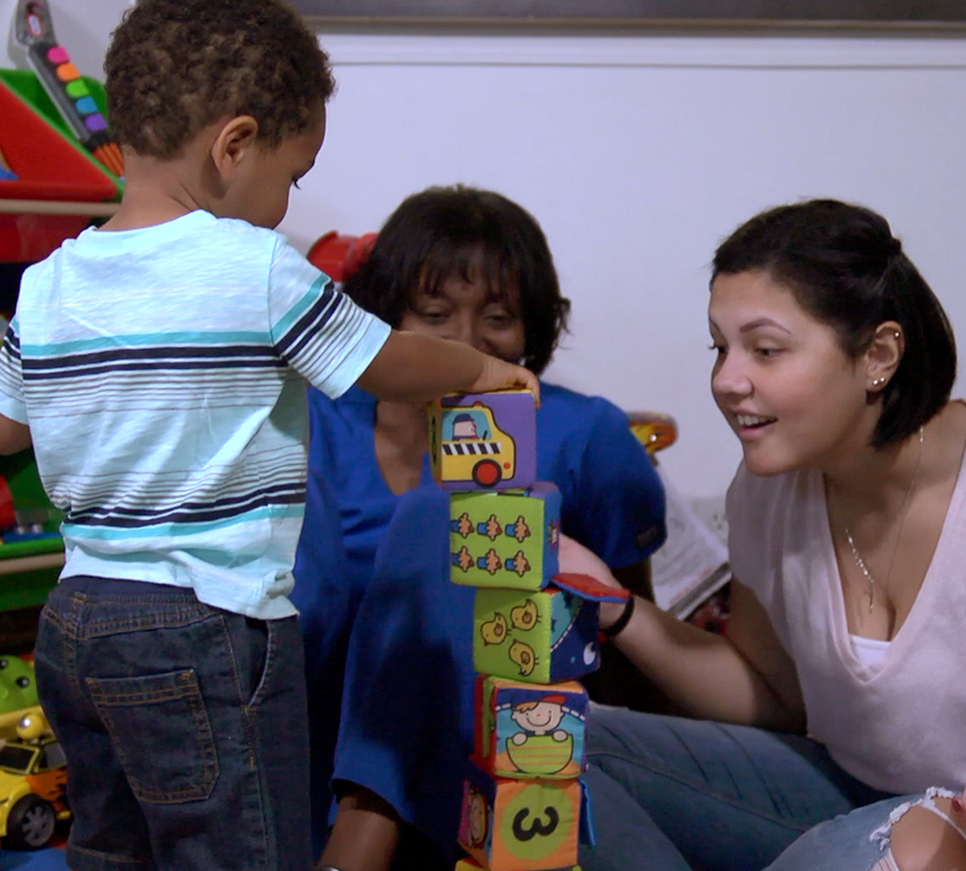 Child stacking blocks with mom and nurse.