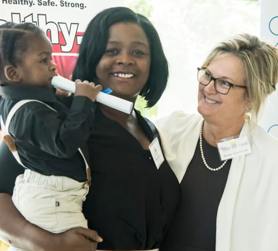 Mother holding son with nurse.
