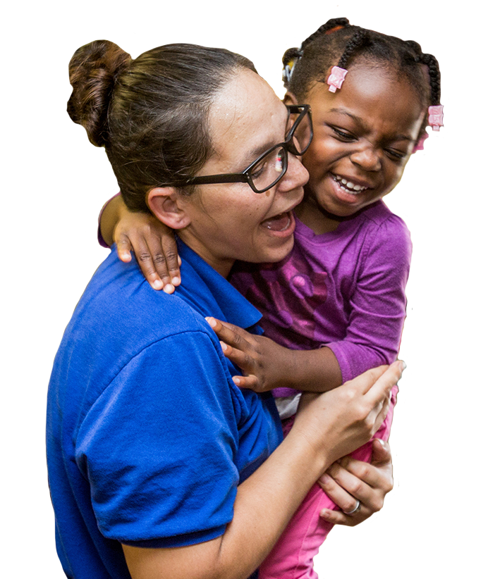 Child care provider holding young girl in her arms.