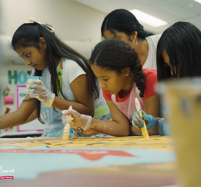 A group of girls painting a mural.