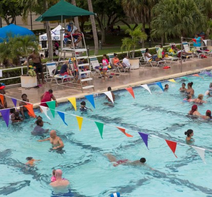 An aerial view of Lake Lytal Pool filled with families playing in the water, as a lifeguard in a chair keeps watch.