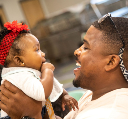 A local father and baby smile at each other and celebrate at a CSC-Funded BRIDGES event.