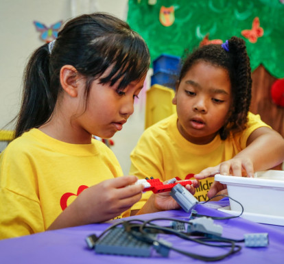Two girls work with robotics at summer camp.