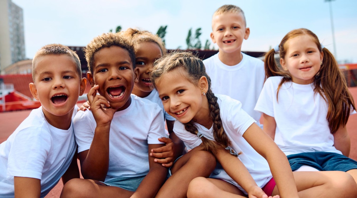 a diverse group of smiling children in white t-shirts.