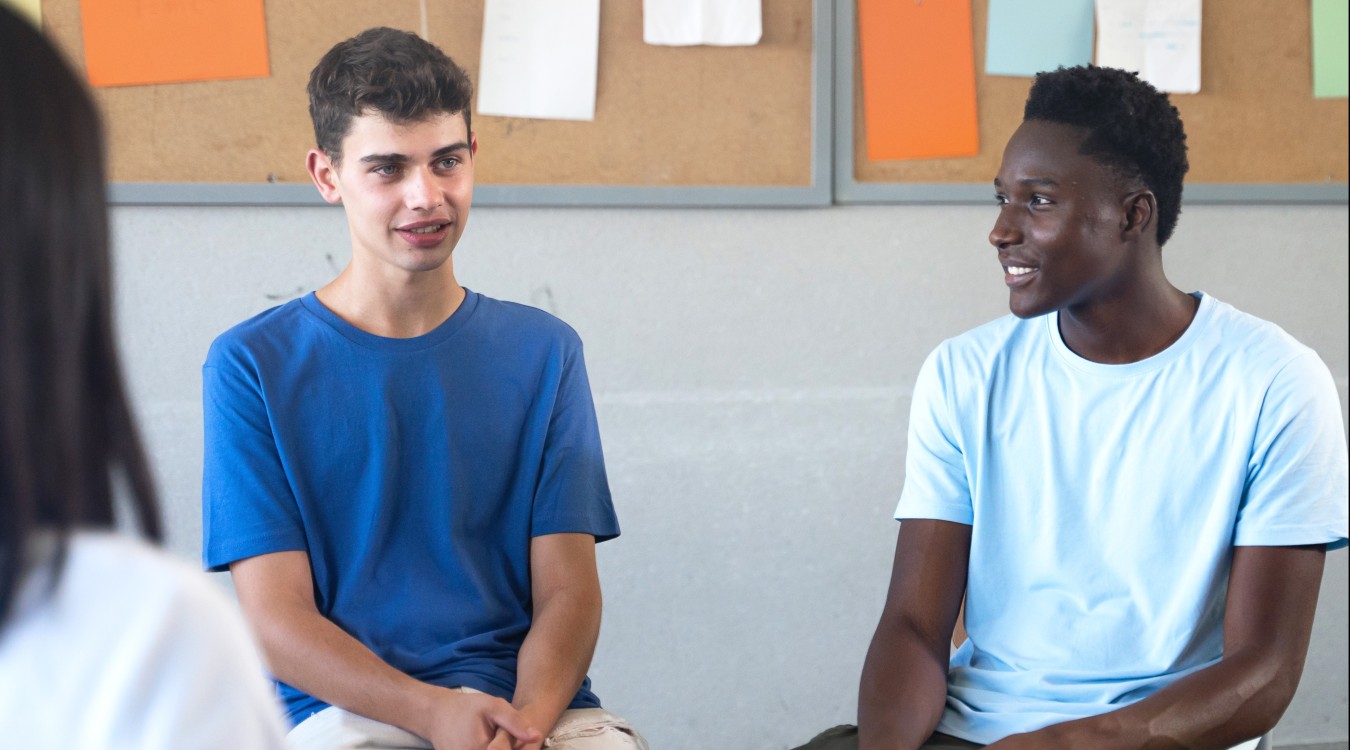 Teens sit on chairs in a circle sharing their thoughts.