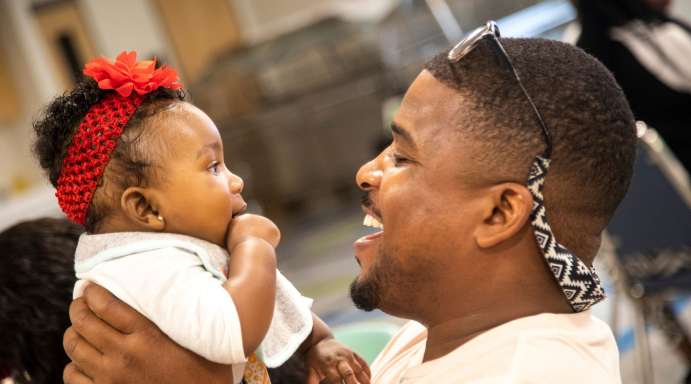 A local father and baby smile at each other and celebrate at a CSC-Funded BRIDGES event.