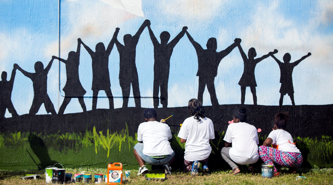 Youth from a local Teen Outreach Program paint a mural of children holding hands.