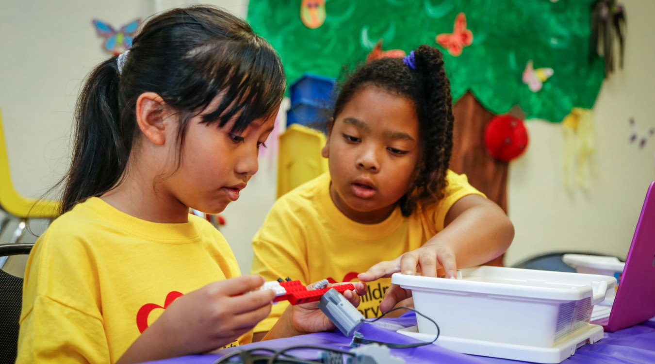 Two girls work with robotics at summer camp.