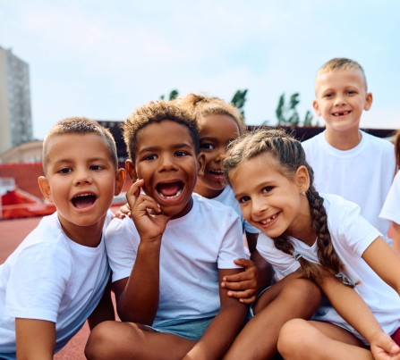 a diverse group of smiling children in white t-shirts.