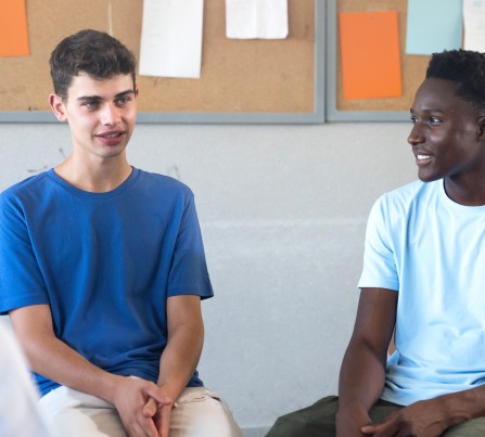 Teens sit on chairs in a circle sharing their thoughts.