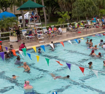 An aerial view of Lake Lytal Pool filled with families playing in the water, as a lifeguard in a chair keeps watch.