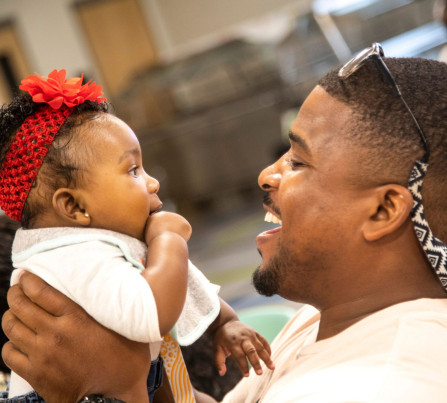 A local father and baby smile at each other and celebrate at a CSC-Funded BRIDGES event.