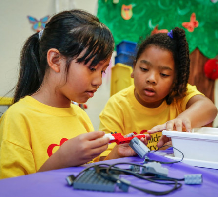 Two girls work with robotics at summer camp.
