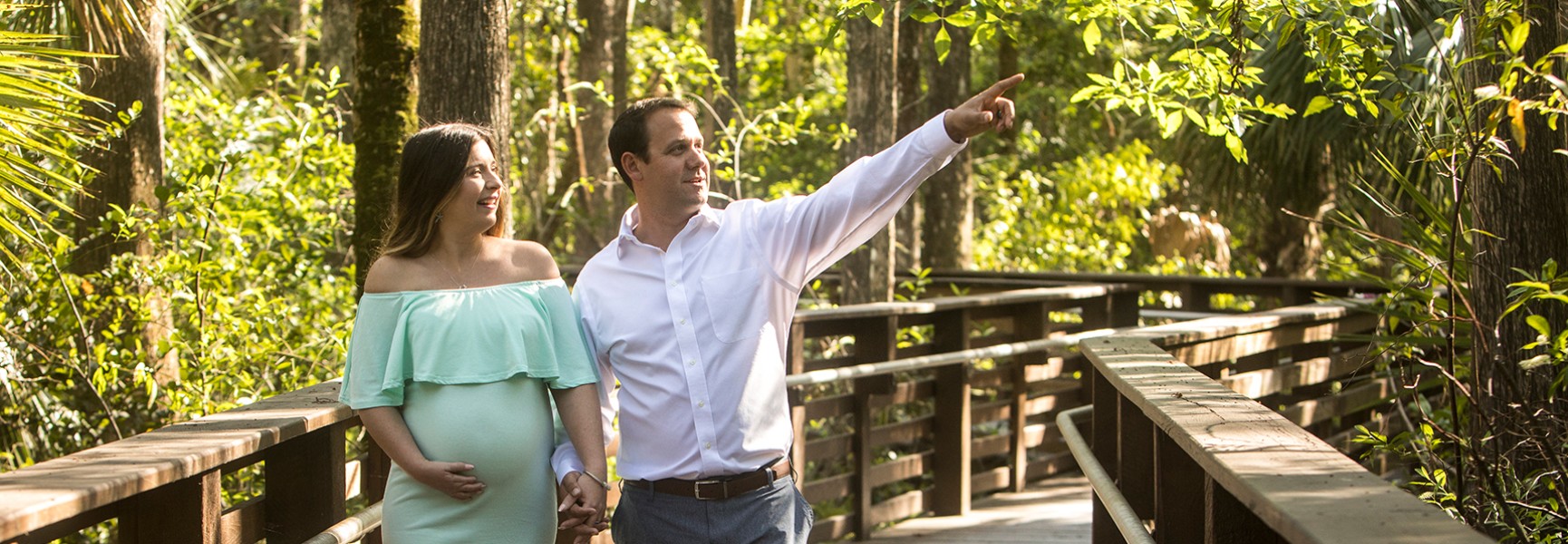 Pregnant woman with man walking in park.