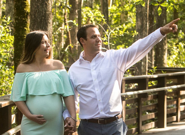 Pregnant woman with man walking in park.