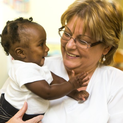 Smiling child care worker holding baby