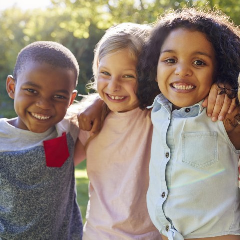 Young children with artms around each other.