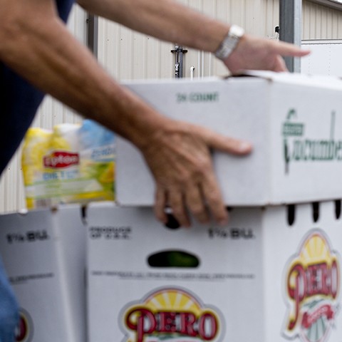 Man stacks boxes of fresh produce outside The Palm Beach County Food Bank