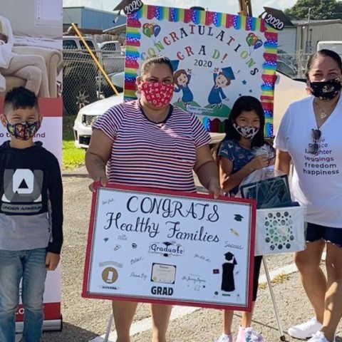 Family holding sign congratulating them on graduation from the Healthy Families program.