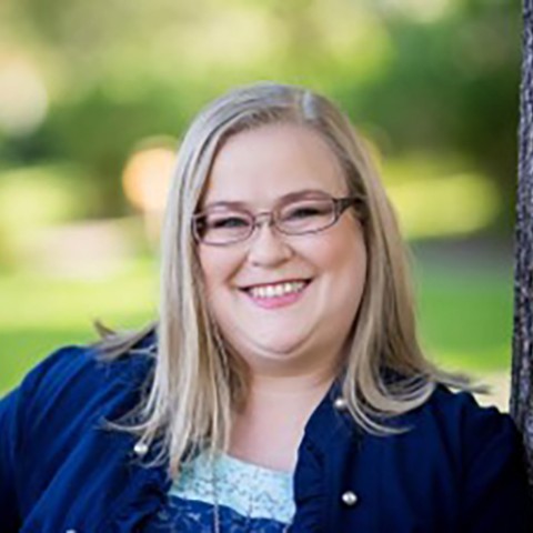 Woman smiling while leaning on tree.