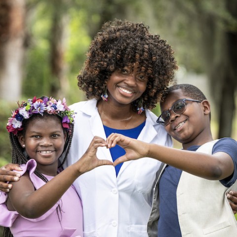 Mother with daughter and son making a heart sign with hands.