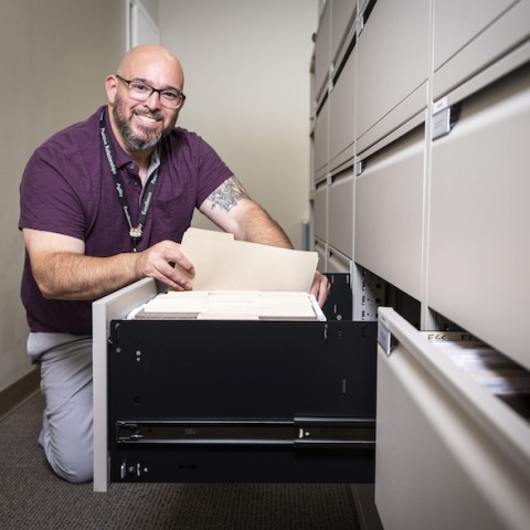 Man filing files in a cabinet.