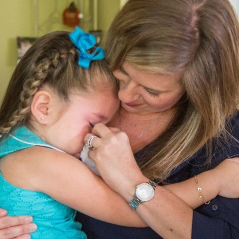 A mother holding a tissue comforting her crying daughter.