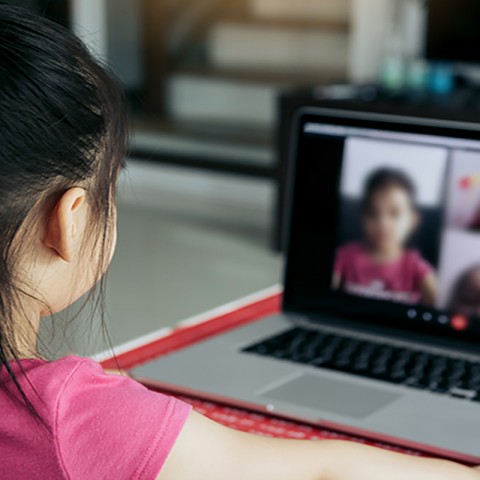 Little girl looking at a laptop, participating in distance learning. 