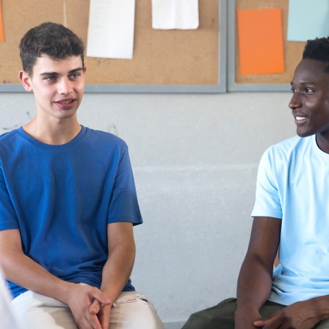 Teens sit on chairs in a circle sharing their thoughts.