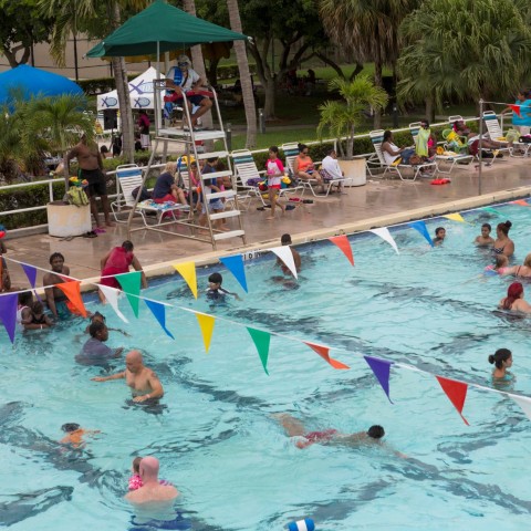 An aerial view of Lake Lytal Pool filled with families playing in the water, as a lifeguard in a chair keeps watch.