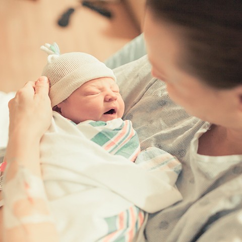 Mother in hospital holds newborn baby in her arms. 