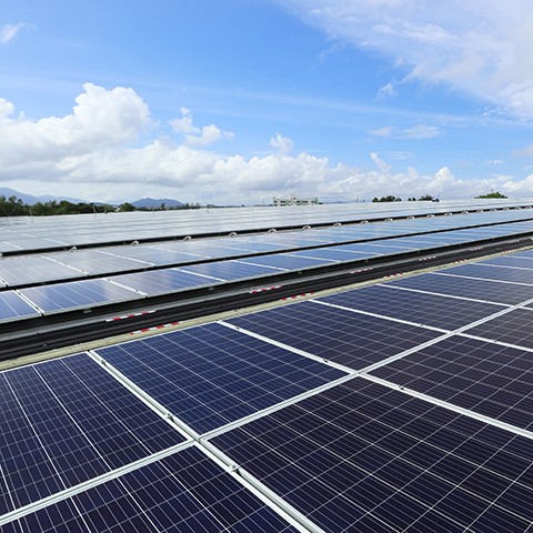 Solar panels on top of a building with a mix of blue skies and clouds in the background.