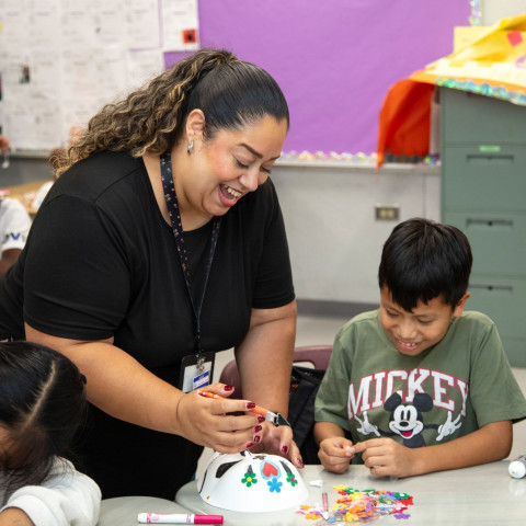 A Teen Outreach Program staffer works with students on an art project.