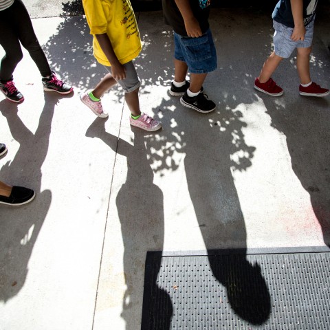 Young children's feet walking in a line outside at a child care center.