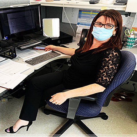 Mercedes Battle sits at a desk surrounded by computers and papers. She works for the Department of Health's Healthy Beginnings Nurses program, overseeing the team of three Spanish-speaking family support workers and two Creole-speaking family support workers.