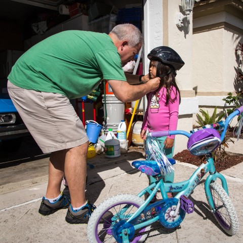 Dad fitting young daughter's bike helmet outside