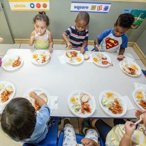 Young children sitting at a table eating together