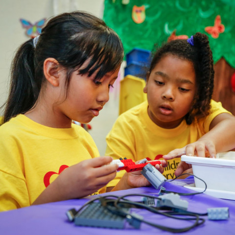 Two girls work with robotics at summer camp.